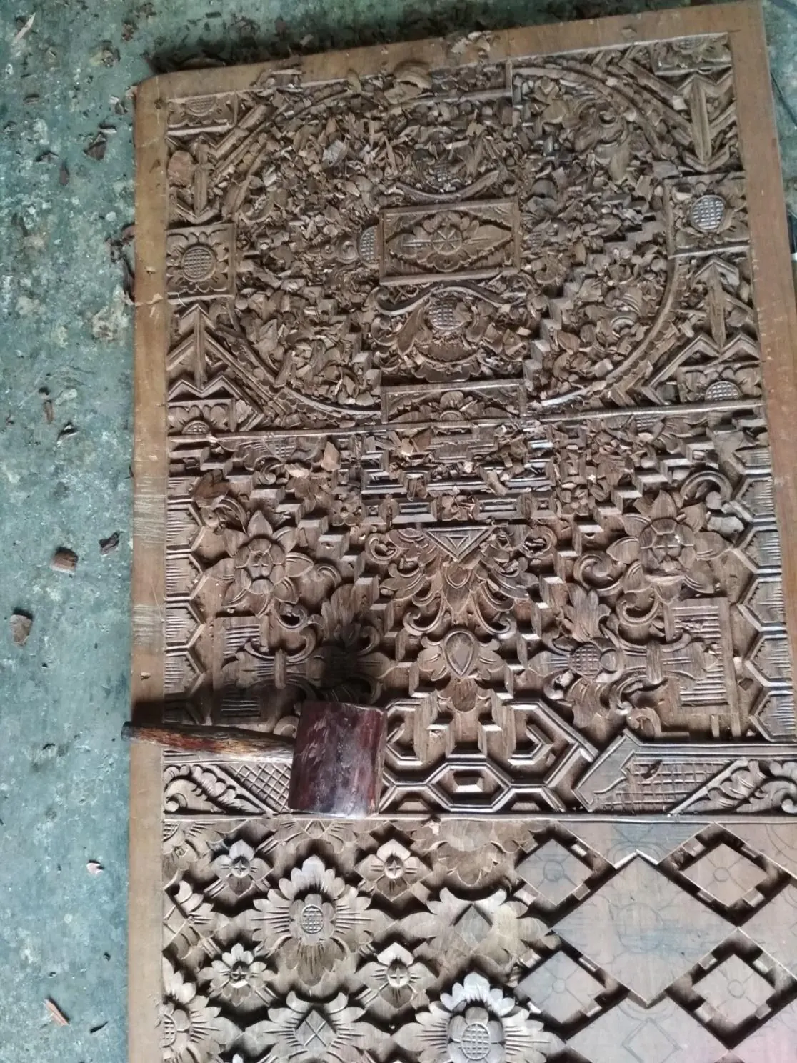 Detailed Balinese wood carving panel — Patra Punggel scrollwork in a workshop, in progress