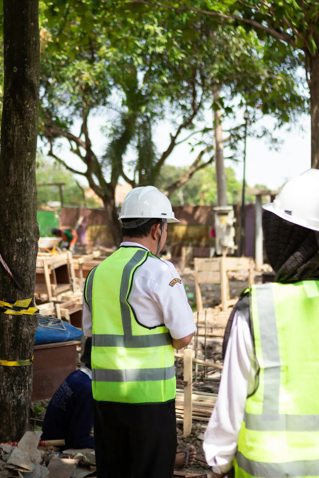 Site supervisor in a hard hat and safety vest overseeing an active construction site
